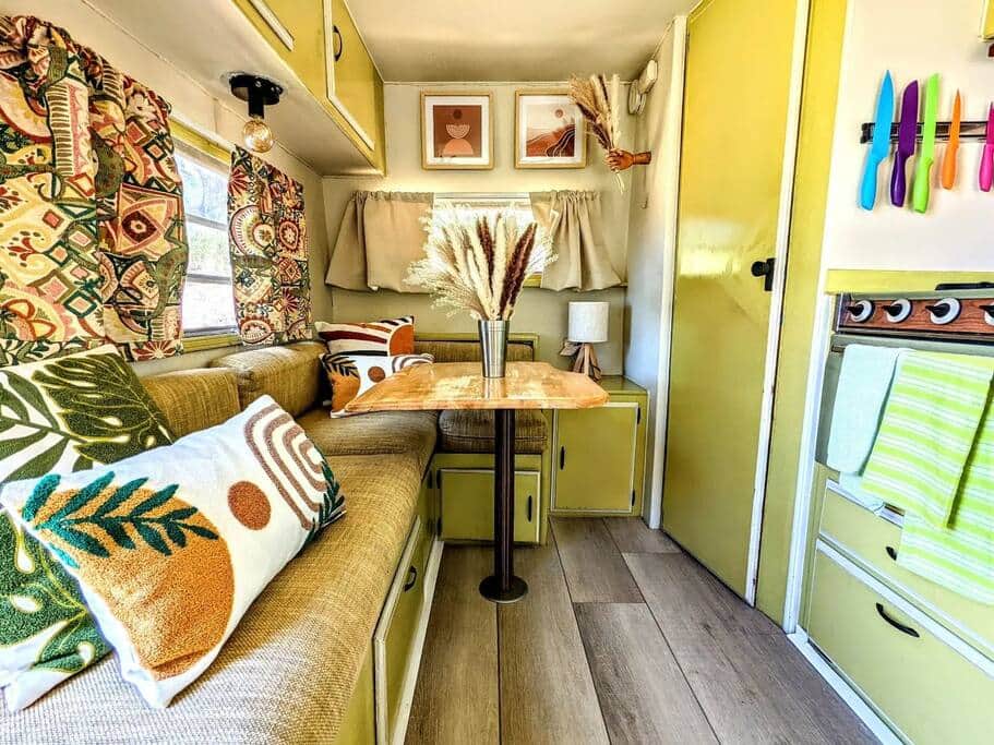 Bohemian vintage RV interior with a dinette booth, pampas grass centerpiece and boho pillows