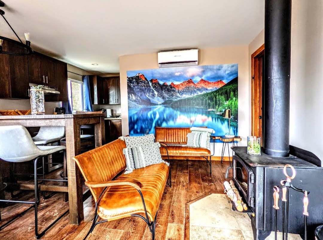Cozy cottage interior with leather bench seating, wood-burning stove and mountain lake mural