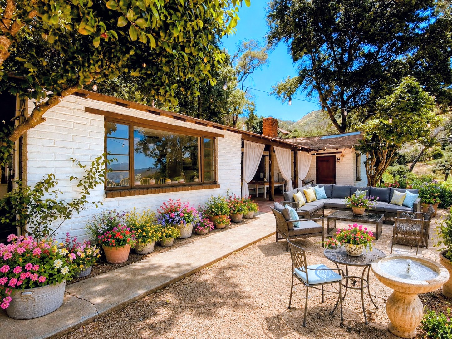 Charming white Hideout Mountain guest house with colorful flower planters and a shaded patio lounge set